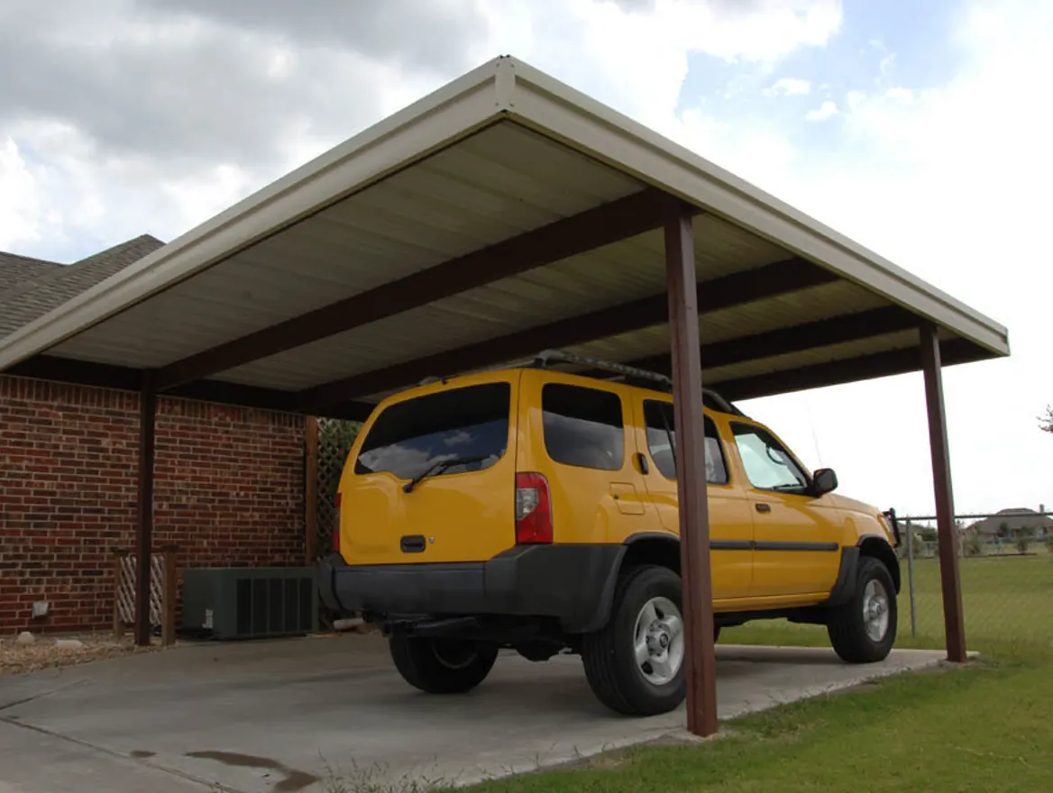 A metal carport beside a brick house with a yellow SUV parked under it